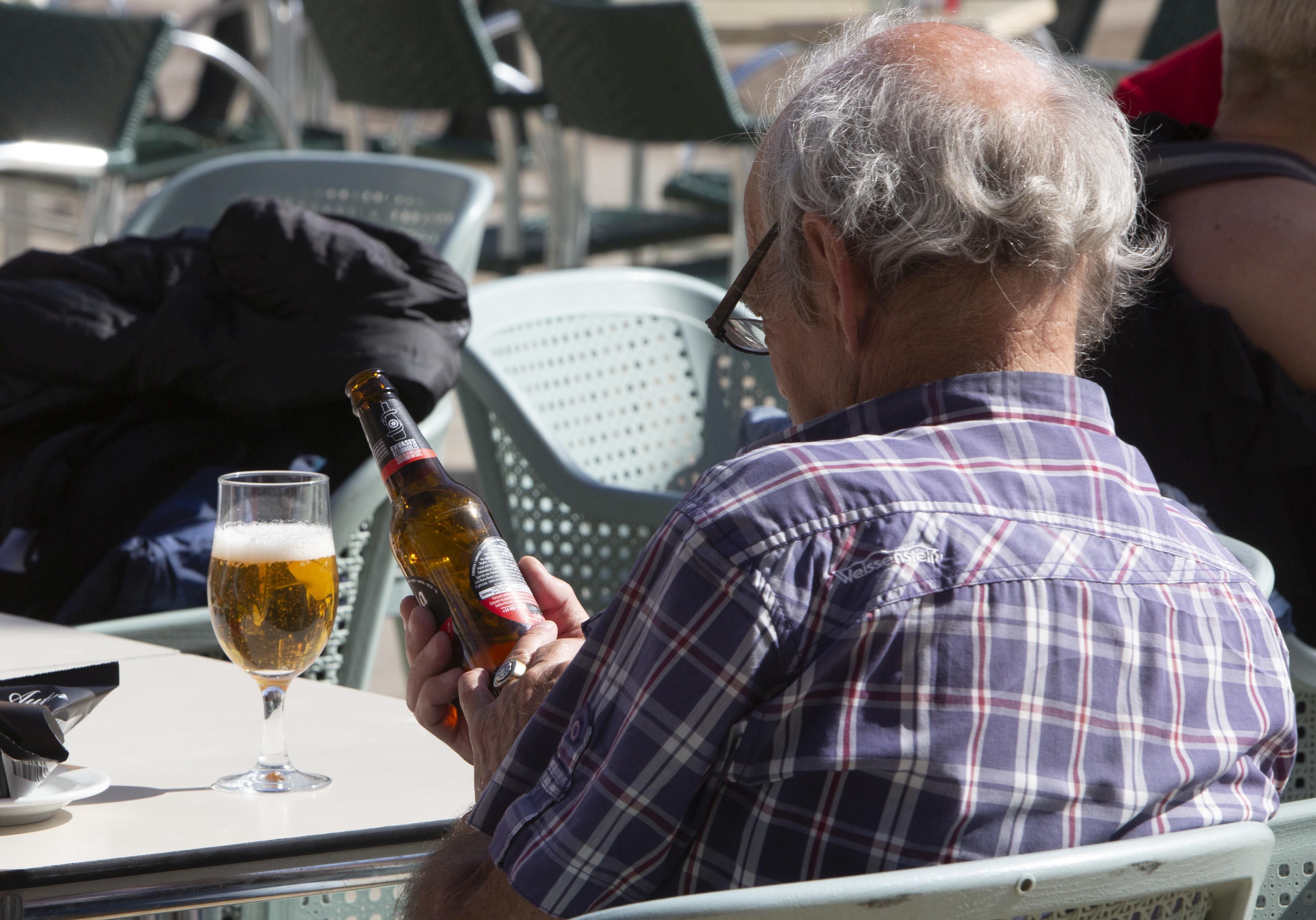 Un cliente lee la etiqueta de una cerveza en una terraza