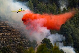 Una avionetya lanza líquido de extinción de incendios sobre el fuego declarado en Tàrbena.