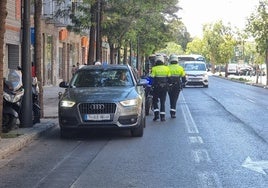 Agentes de la Policía Local, junto a un coche que circula por el carril bus.