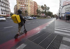 Un usuario de patinete recorre el carril bici de las grandes vías en el cruce con Ángel Guimerà.