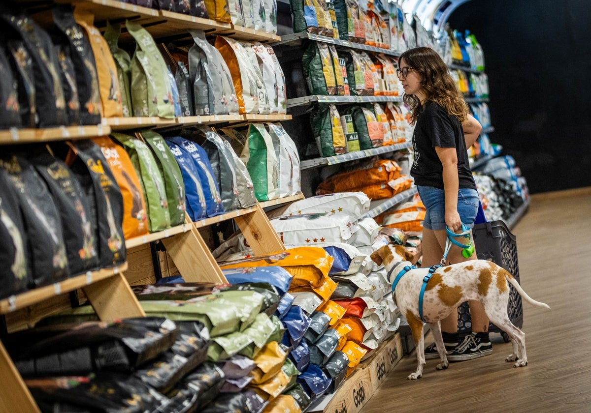 Una joven, con su perro en una tienda de alimentación animal.