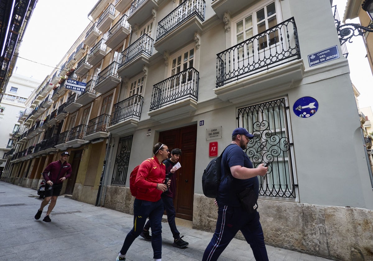 Un grupo de turistas pasan ante un bloque de apartamentos.