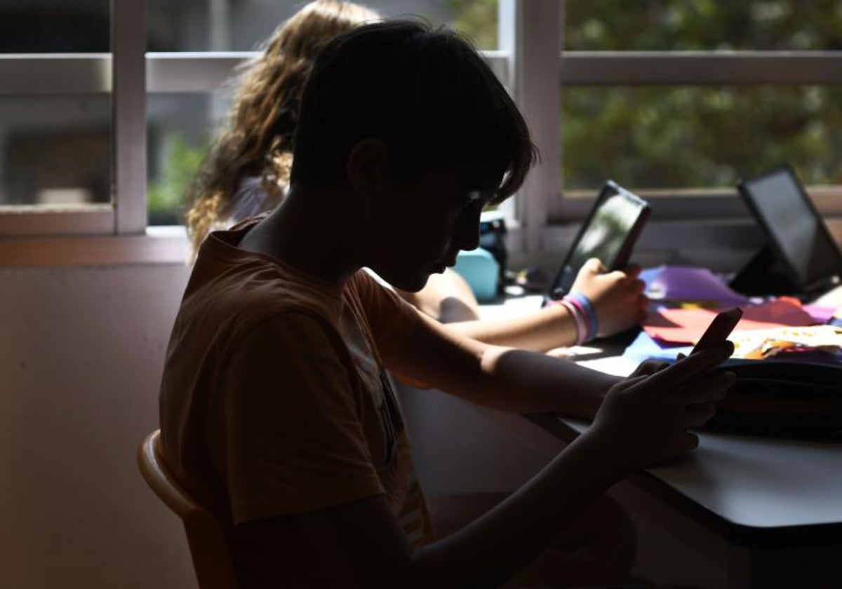 Una niña consulta su móvil en un colegio.