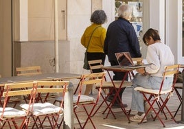 Una mujer, con su ordenador portátil en la terraza de un bar en Valencia.