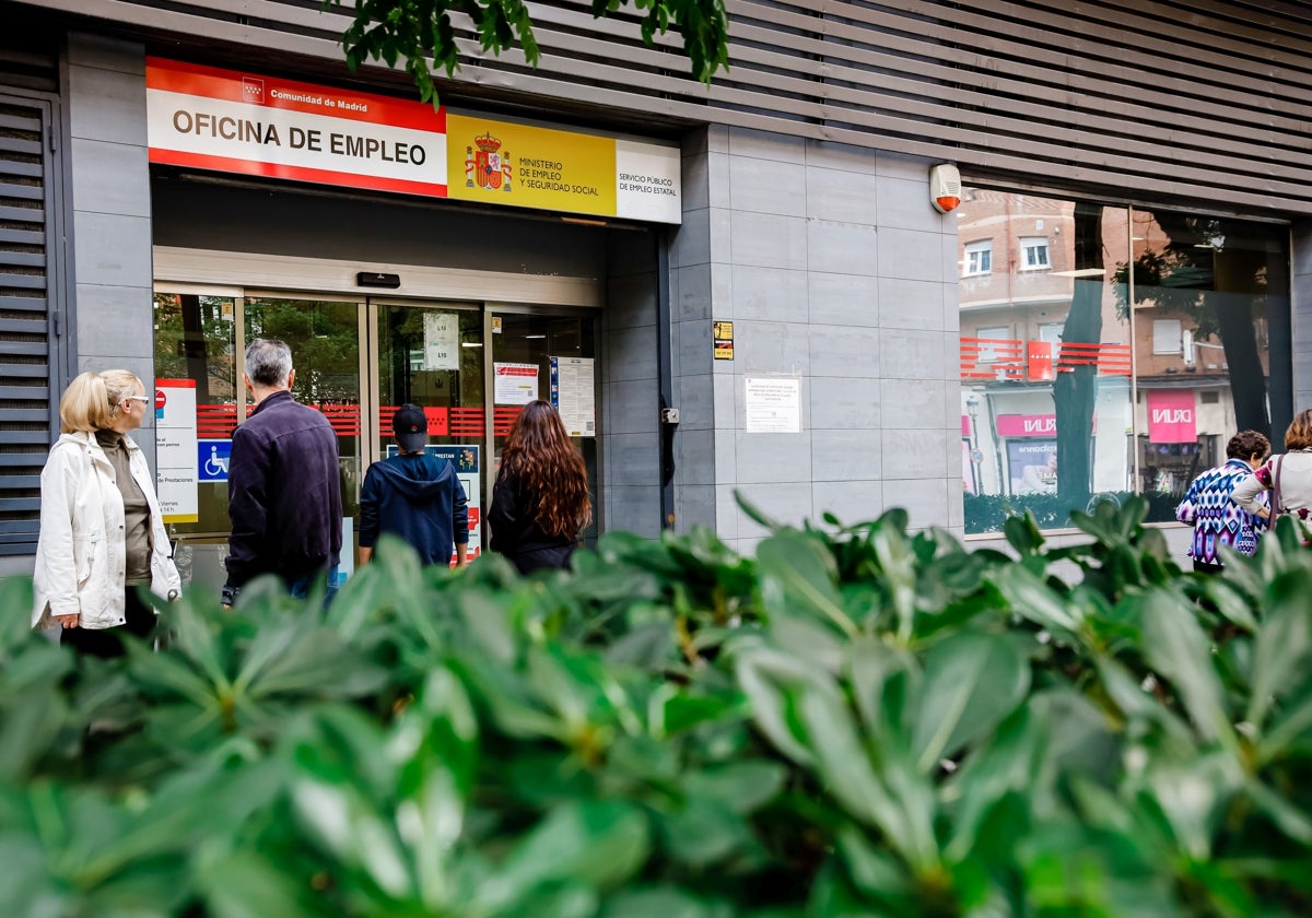 Varias personas hacen cola en una oficina del paro.