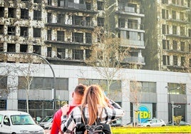 Una pareja contempla el edificio calcinado de Campanar.