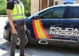 Un policía junto a un coche patrulla.