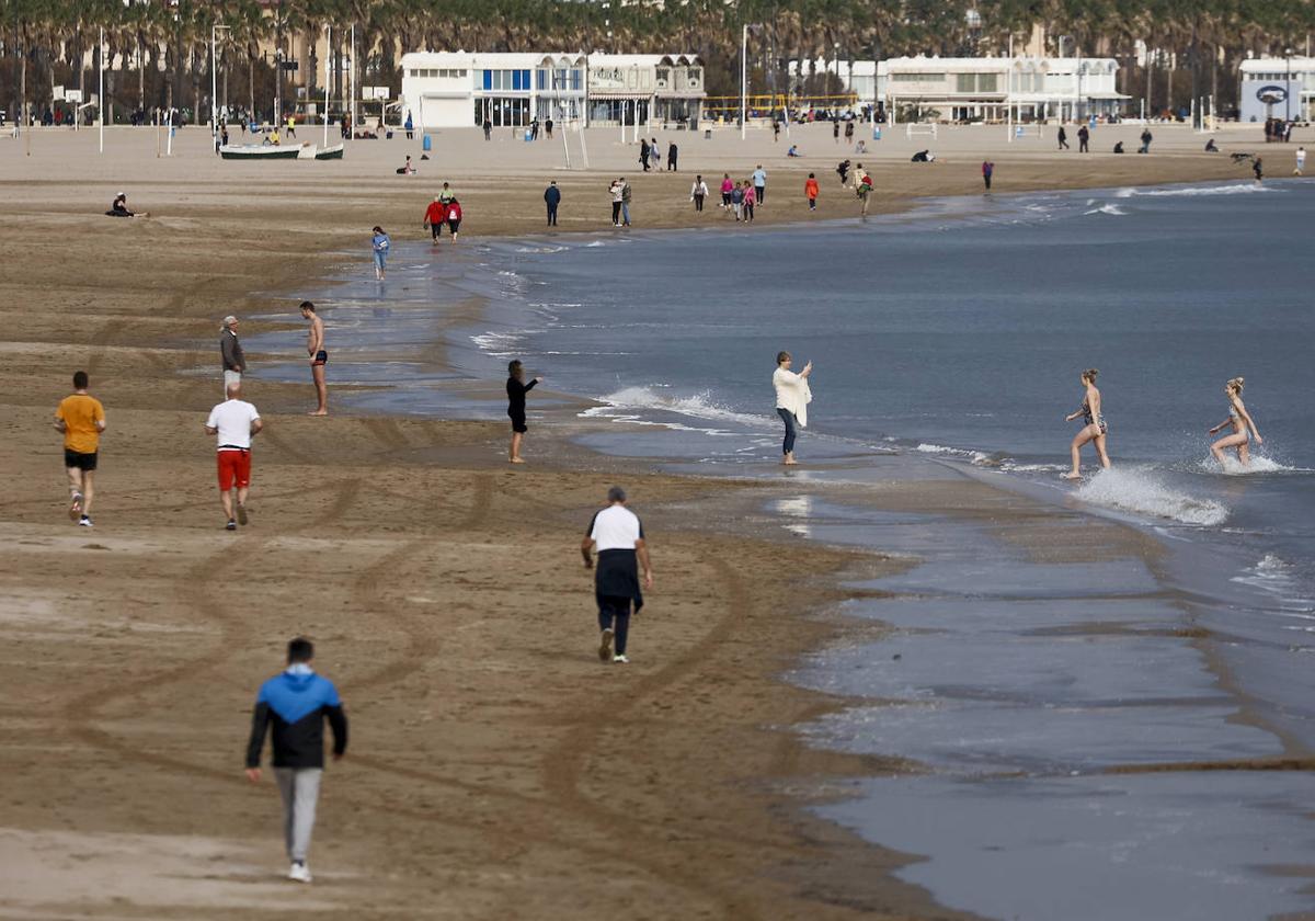 Varias personas disfrutan del buen tiempo en la playa de la Malvarrosa