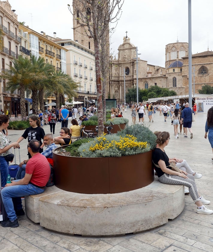 Imagen secundaria 2 - Maceteros de metal negros y en tono oxidado de distinto tamaño y otros con bancos circulares, en la palza de la Reina.