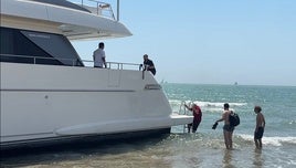 Uno de los miembros de la tripulación recibe a los peritos en el yate encallado en la playa de Pinedo.