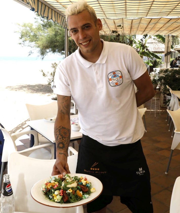 Imagen secundaria 2 - La cocina del restaurante con varias paellas individuales en marcha, una ración de sardinas y el joven Eric con una ensalada con palomitas dulces.
