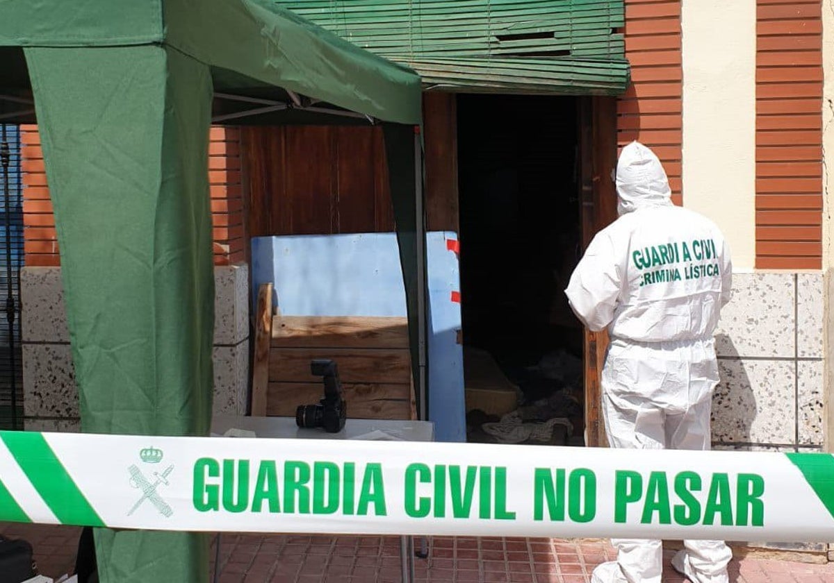 Un agente del Servicio de Criminalística de la Guardia Civil en la puerta de la casa de la víctima.