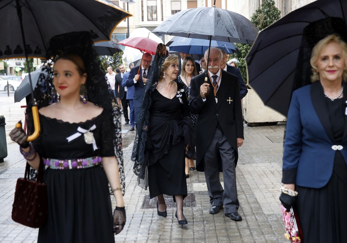 Imagen principal - Celebración de la procesión claustral y asistentes al acto, con paraguas.