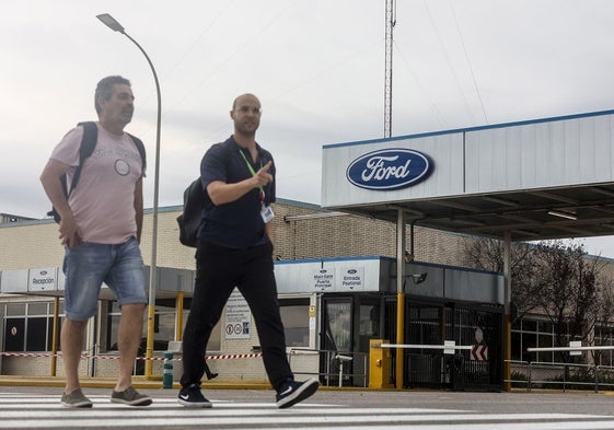 Dos trabajadores, frente a la puerta de acceso a la planta de Ford en Almussafes.