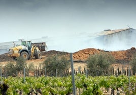 UNa excavadora intenta sofocar el incendio en la planta de Requena.