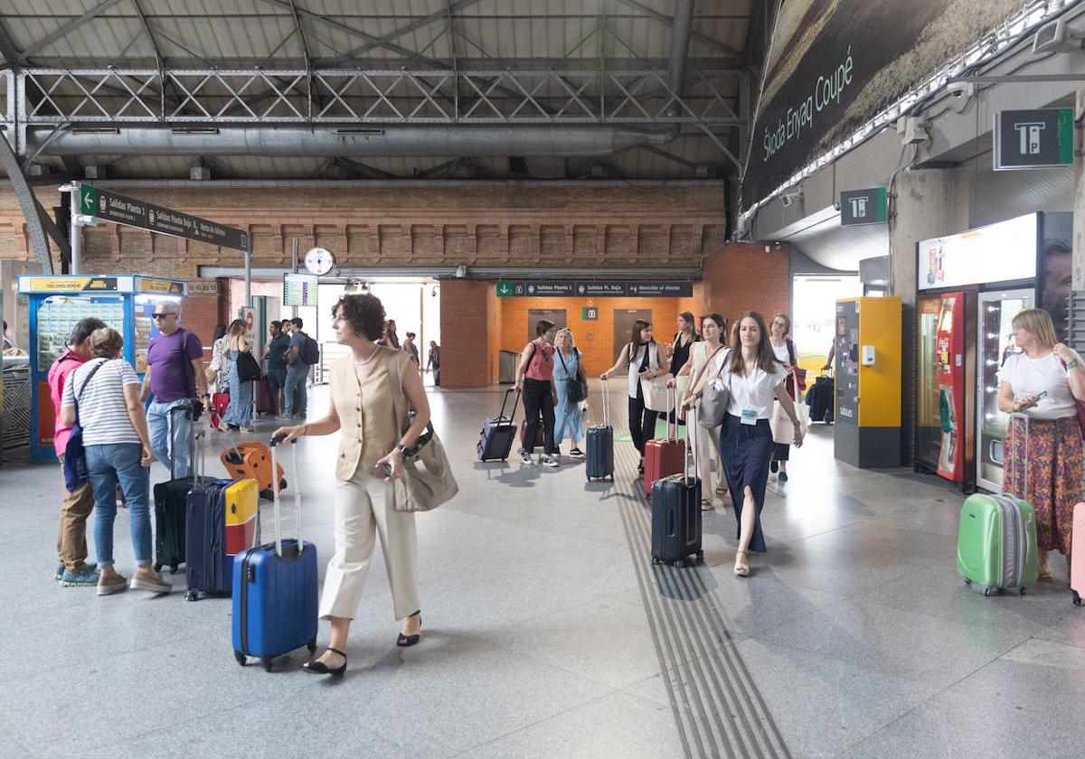 Varias personas esperando en la estación de tren para comenzar sus vacaciones.