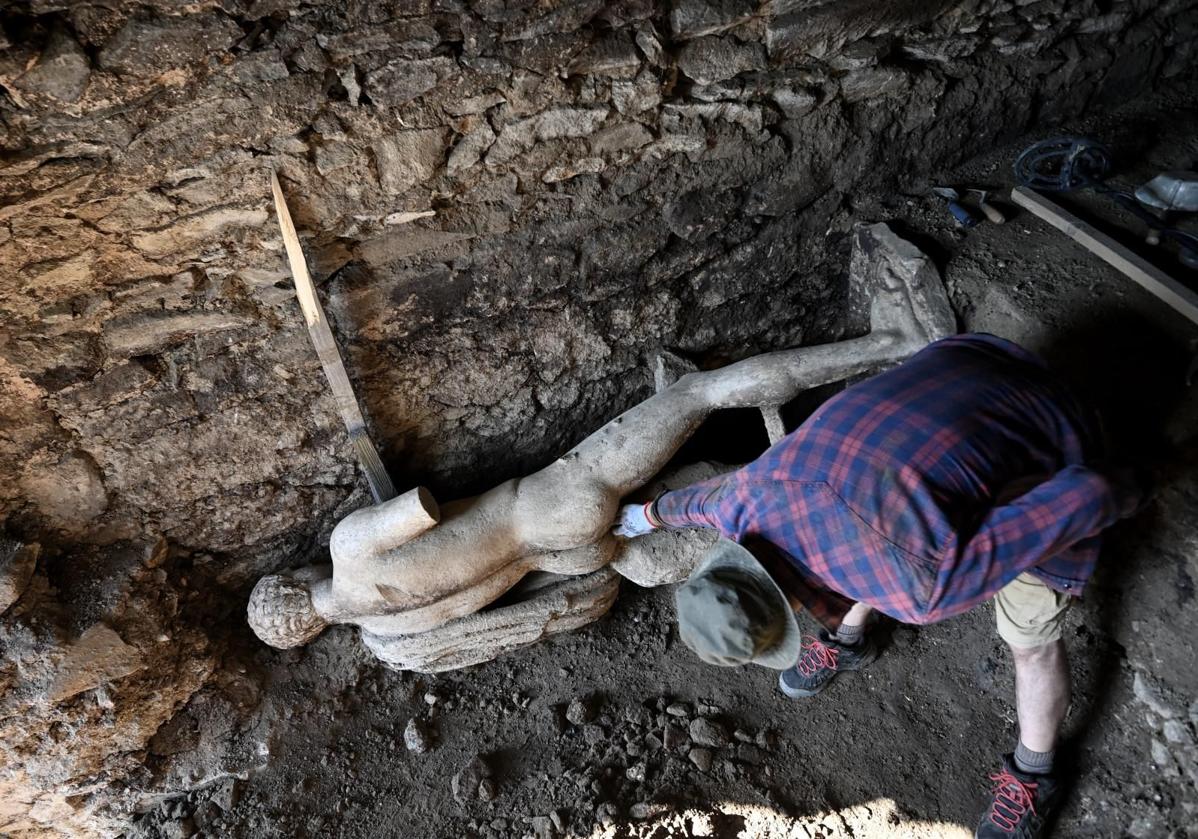 Un arqueólogo examina la estatua de Hermes.