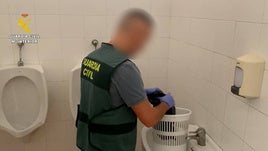 Un agente de la Guardia Civil extrayendo el teléfono móvil de la papelera