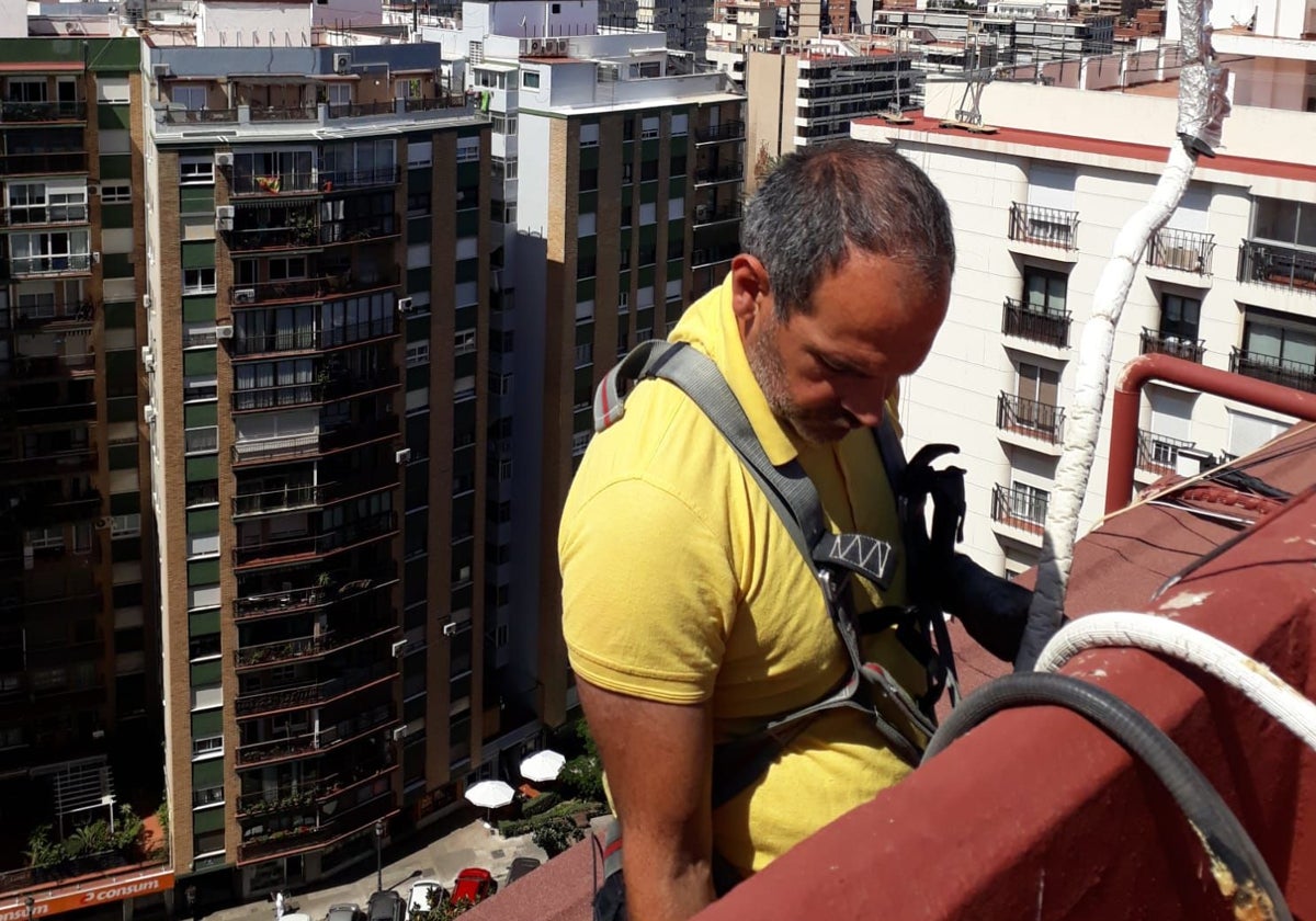 Luis Montero, en plena faena, durante la instalación de un aparato climatizador en una repisa de Valencia.