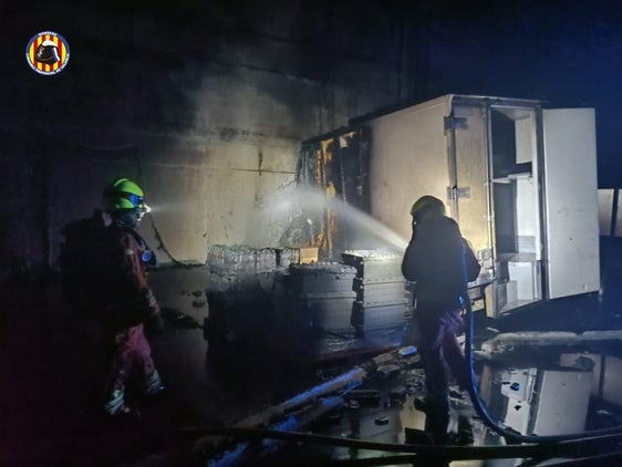 Los bomberos, durante la extinción del incendio en la nave de Alzira.