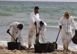 Operarios trabajan en las playas del sur de Valencia afectadas por el alquitrán.