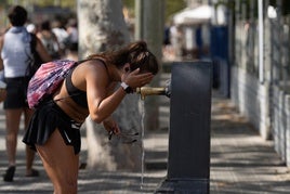 Una joven se refresca en una fuente.