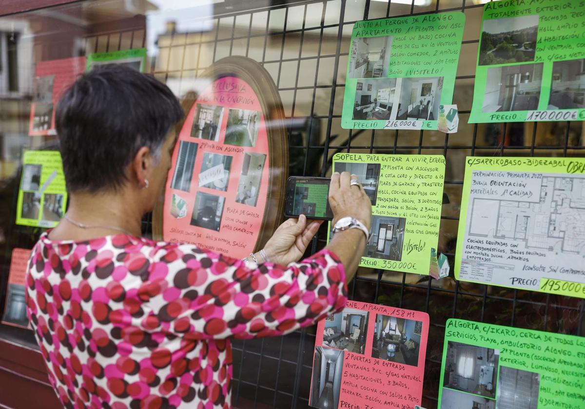 Una mujer fotografía un anuncio de vivienda en una inmobiliaria.