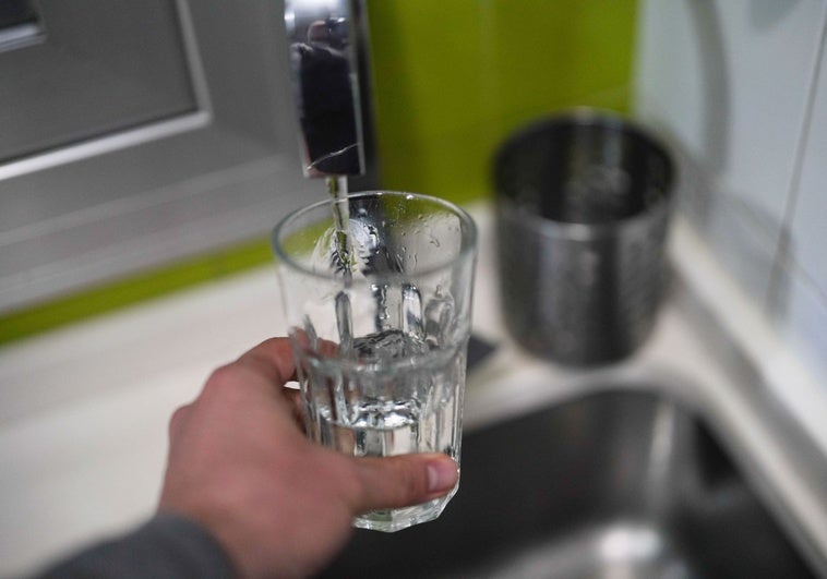 Una persona llena un vaso con agua del grifo.