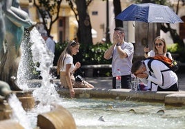 Un grupo de personas se refresca en una fuente en Valencia.