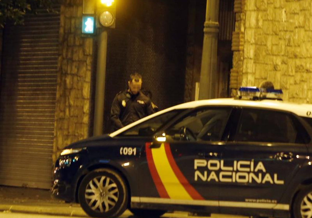 Un policía nacional junto a un coche patrulla.