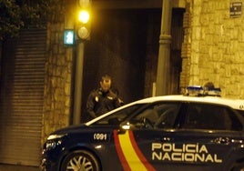 Un policía nacional junto a un coche patrulla.