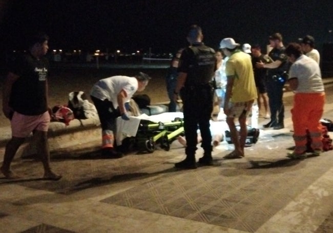 Amigos del joven que sufrió la picadura, sanitarios y policías locales en el paseo marítimo.