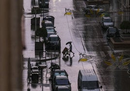 Un joven se protege de la lluvia en Elche.