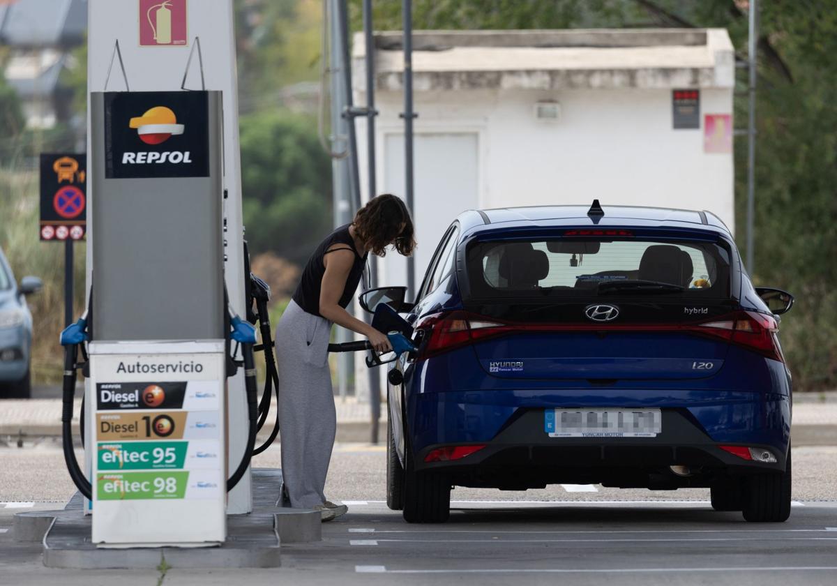 Una mujer echa gasolina a su vehículo.