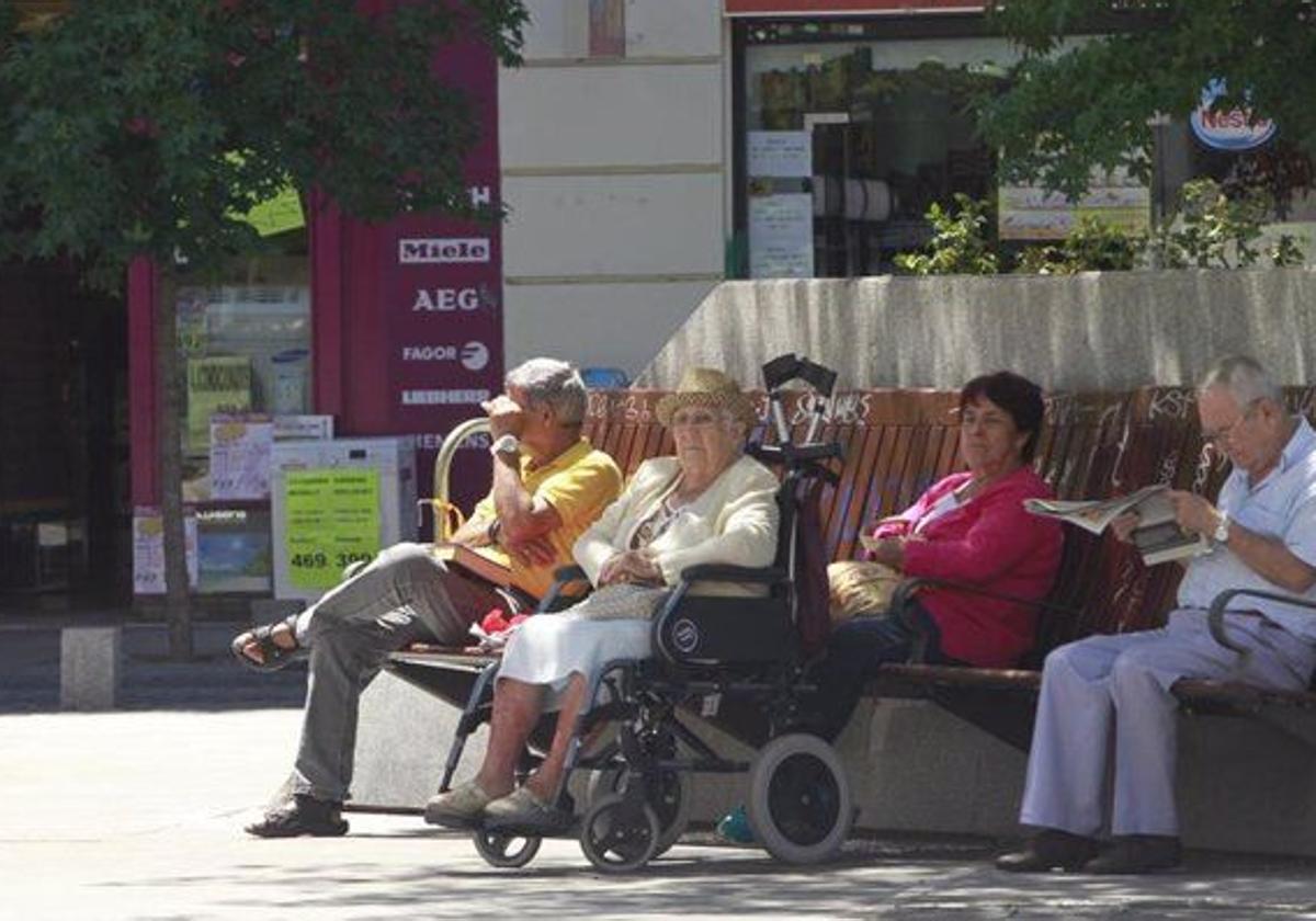 Jubilados tomando el sol en un banco.