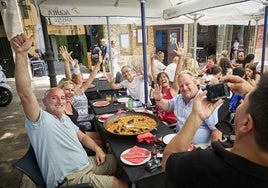 Un grupo de turistas posa para una foto antes de comer una paella en un restaurante.