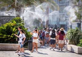 Turistas se protegen del calor en la plaza de la Reina de Valencia.