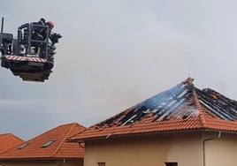 Efectivos del cuerpo de bomberos sofocan las llamas en el techo del inmueble.