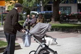 Un hombre mayor pasea por la calle con un carrito de bebé