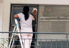 Una trabajadora limpia una ventana.