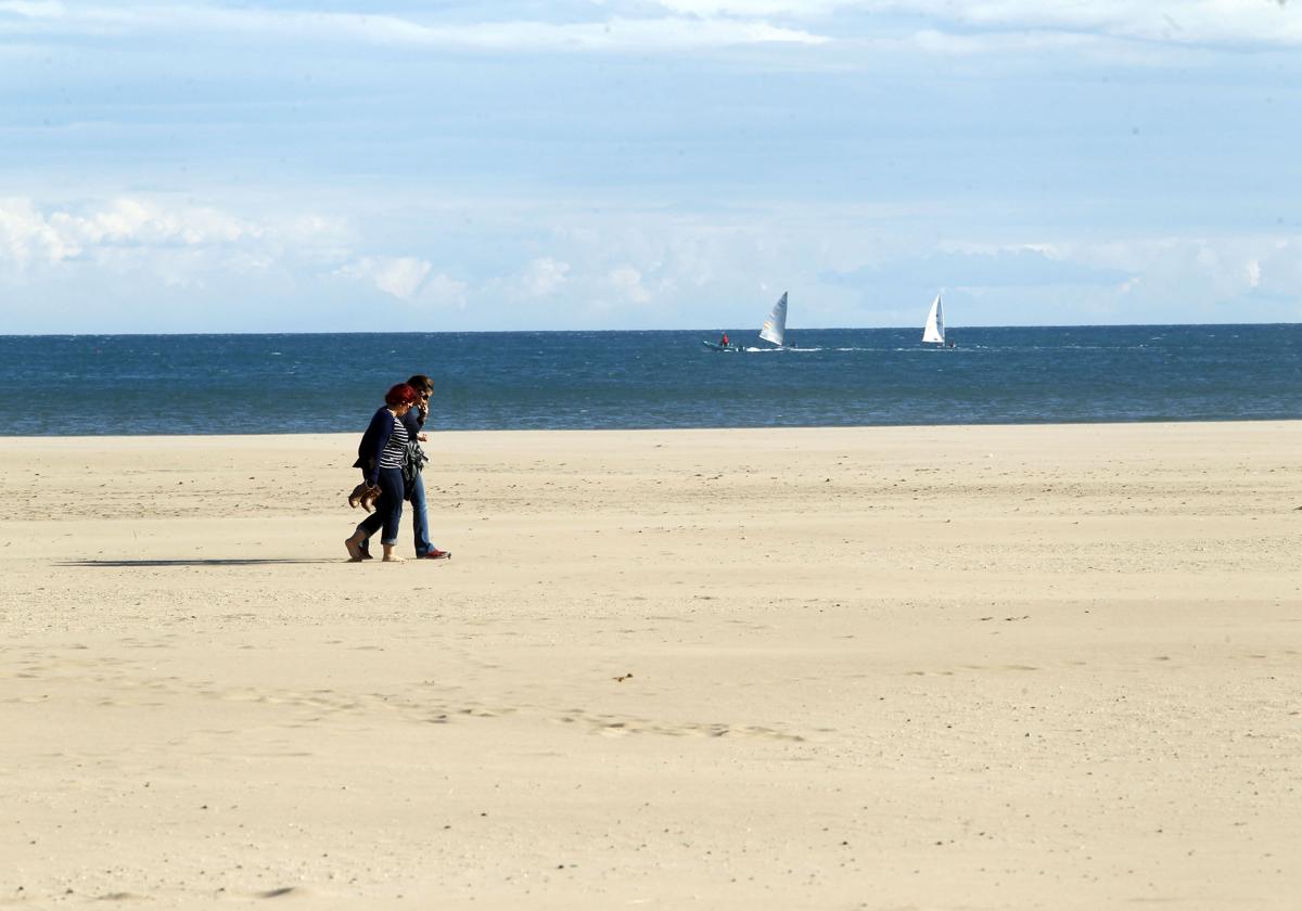 Una pareja pasea por la playa en un día soleado en Valencia.