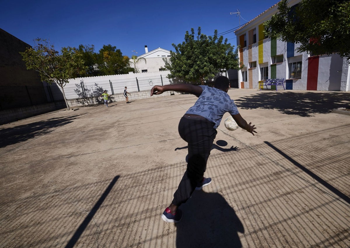 Imagen secundaria 1 - Tres profesoras enseñan a tres alumnos de la escuela de Benissuera (ese día falto uno). Debajo, el mayor de clase (11 años) intenta parar un balón en el recreo. Al lado, el aspecto del aulario desde el exterior.