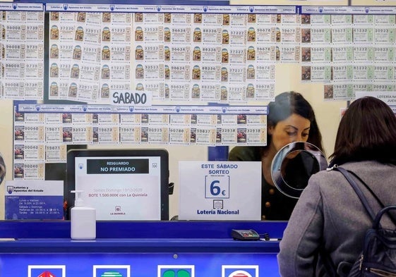 Una mujer compra un décimo en una administración de Lotería.