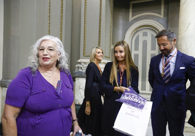 Portavoz de la Coordinadora Feminista de València, entregando una camiseta reivindicativa del movimiento a la edil Cecilia Herrero (Vox) ante la mirada del portavoz del grupo, Juanma Badenas.