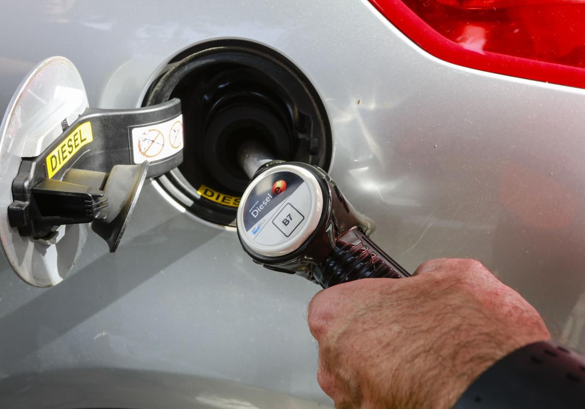 Un conductor llena el déposito de combustible.