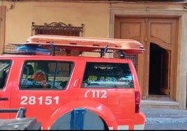 Un vehículo de los bomberos junto a la puerta de la vivienda donde se registró el incendio.