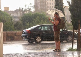 Un joven para un taxi en pleno diluvio este martes en Valencia.