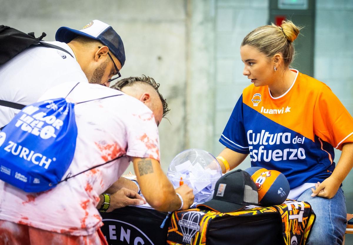 Dos corredores recogen sus dorsales y la bolsa en la Feria del Corredor de la Medio Maratón de Valencia de 2023.