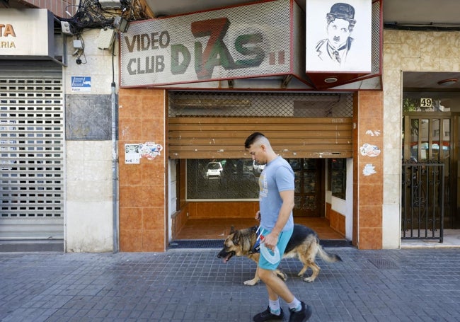 Un joven pasea con su perro junto a la puerta de la planta baja donde retuvieron a varias de las víctimas.