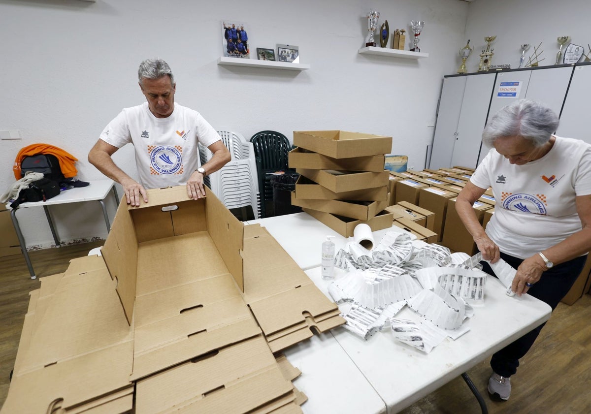 Imagen principal - Los voluntarios de la SD Correcaminos preparan los dorsales que lucirán los corredores.